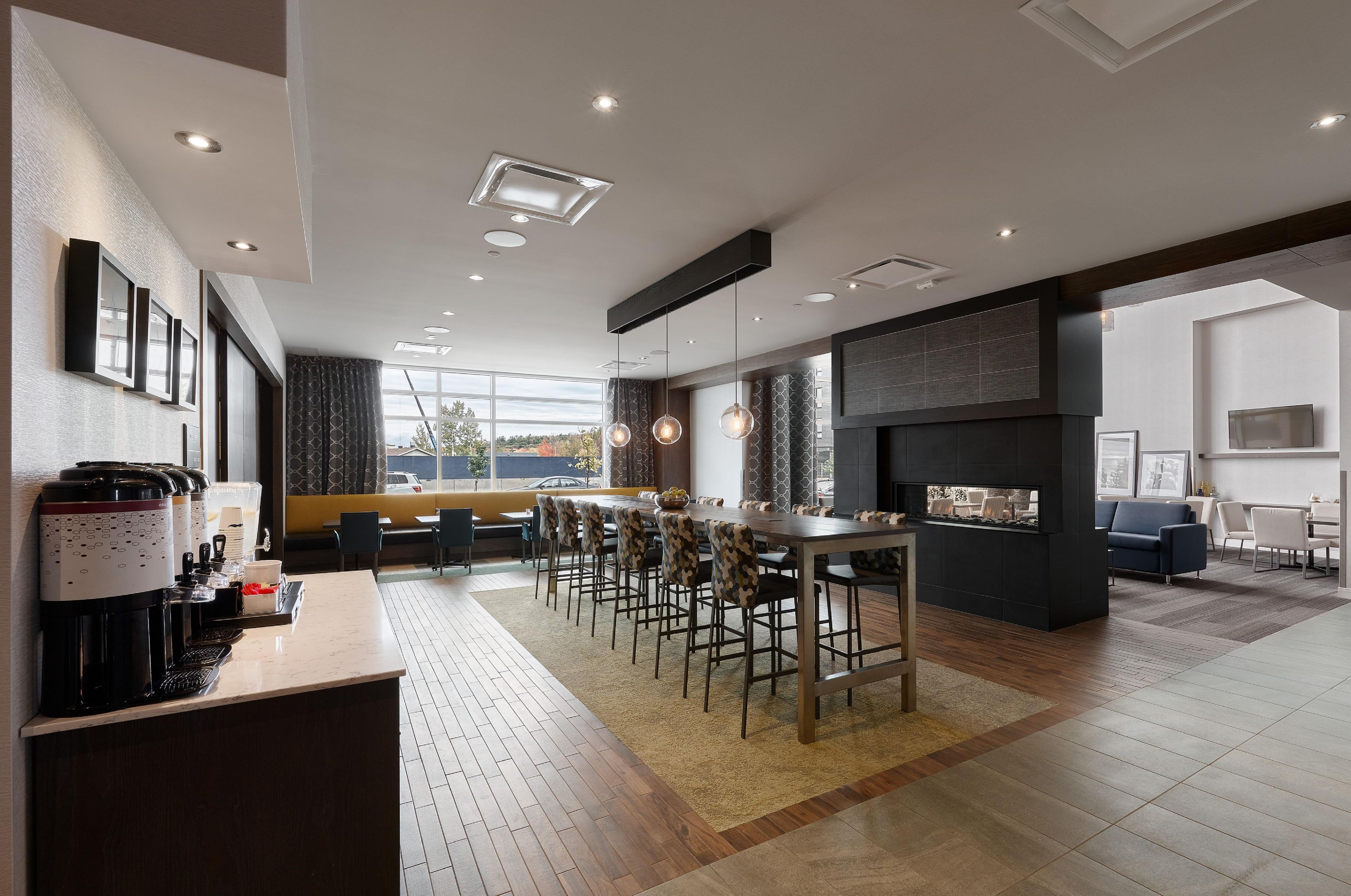 Un moderno vestíbulo de hotel con zona de bar, asientos y chimenea.