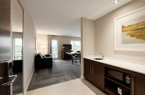 A modern kitchen with a built-in microwave, a sink, and a dining area with a table and chairs. - Hampton Inn & Suites by Hilton Quebec City Levis (Levis)