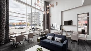Eine moderne Hotelhalle mit einem großen Fenster, einem blauen Sofa und einem Essbereich.