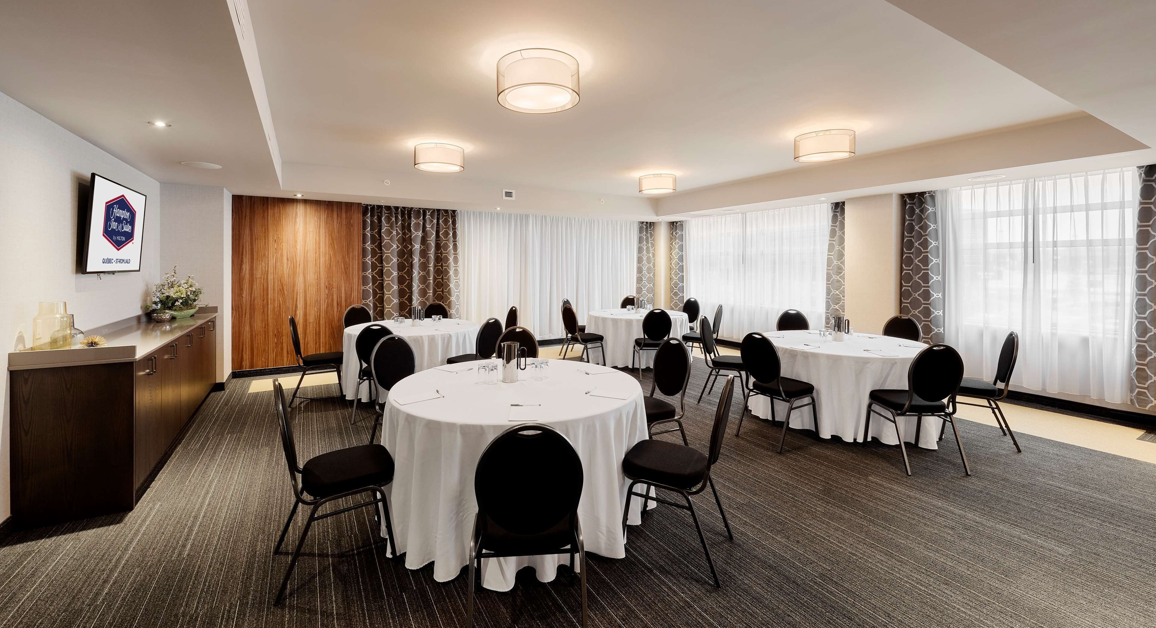 Une salle de conférence équipée de tables rondes, de chaises et d’un comptoir d’accueil.