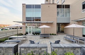 An outdoor patio area with tables, chairs, and umbrellas. - Hampton Inn & Suites by Hilton Quebec City Levis (Levis)