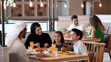 Eine Familie speist in einem Restaurant mit modernem Interieur, darunter freiliegende Ziegelwände und Pendelleuchten.