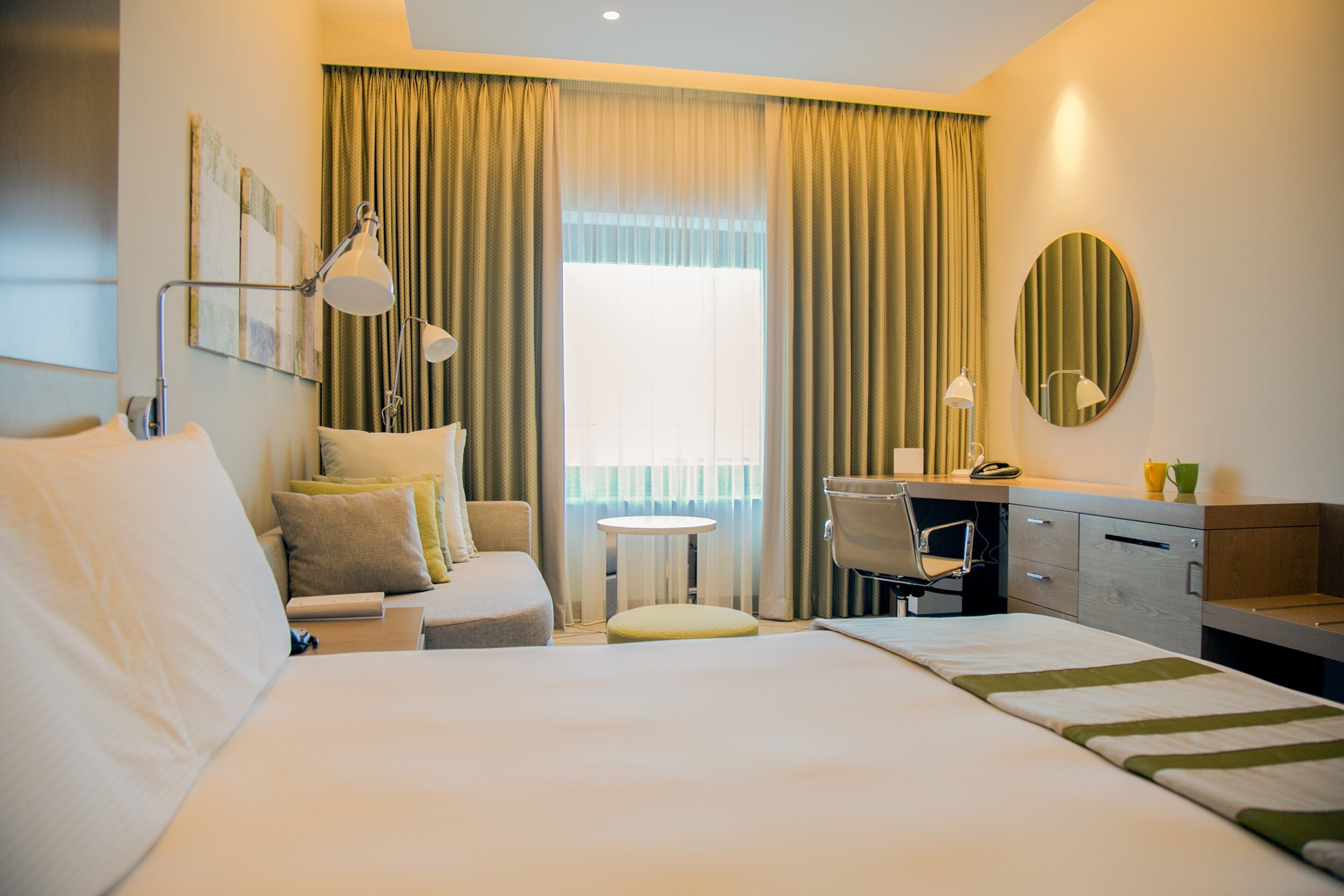 A hotel room with a large bed, a desk, a chair, and a small table.