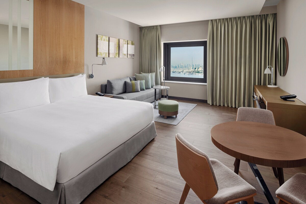 Une chambre d’hôtel avec un grand lit, un canapé, une table à manger et une vue sur le paysage urbain.