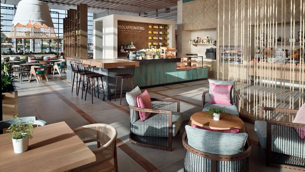 Een modern café met een bar, zitplaatsen en een zichtbaar menubord.