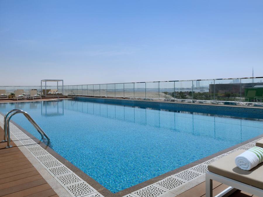 A rooftop pool with clear blue water, a wooden deck, and lounge chairs.