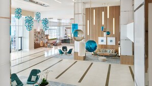 Een ruime lobby met modern zitmeubilair, een decoratieve blikvanger en uitzicht op de eetruimte.