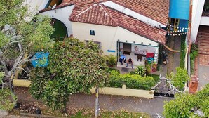 A residential building with a red-tiled roof, a small porch, and a blue awning. - The Pelican Larry Hostel (Cali)
