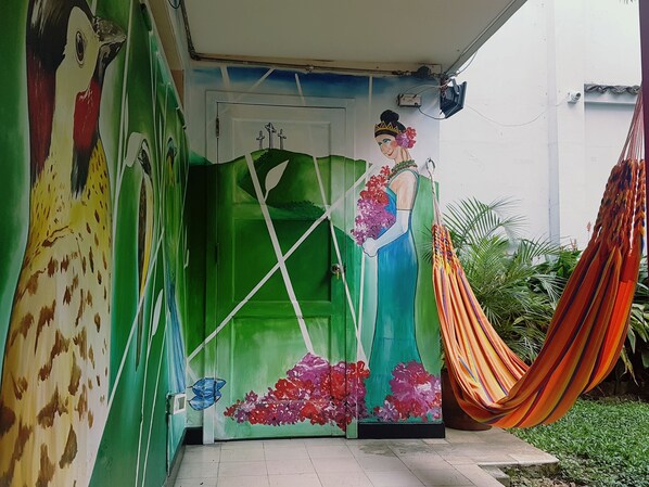 A colorful mural on a building's exterior, a green door, and a hammock. - The Pelican Larry Hostel (Cali)