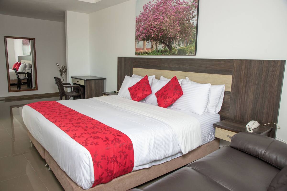 Una habitación de hotel con una cama grande, un escritorio, una silla, una mesita de noche y un teléfono.