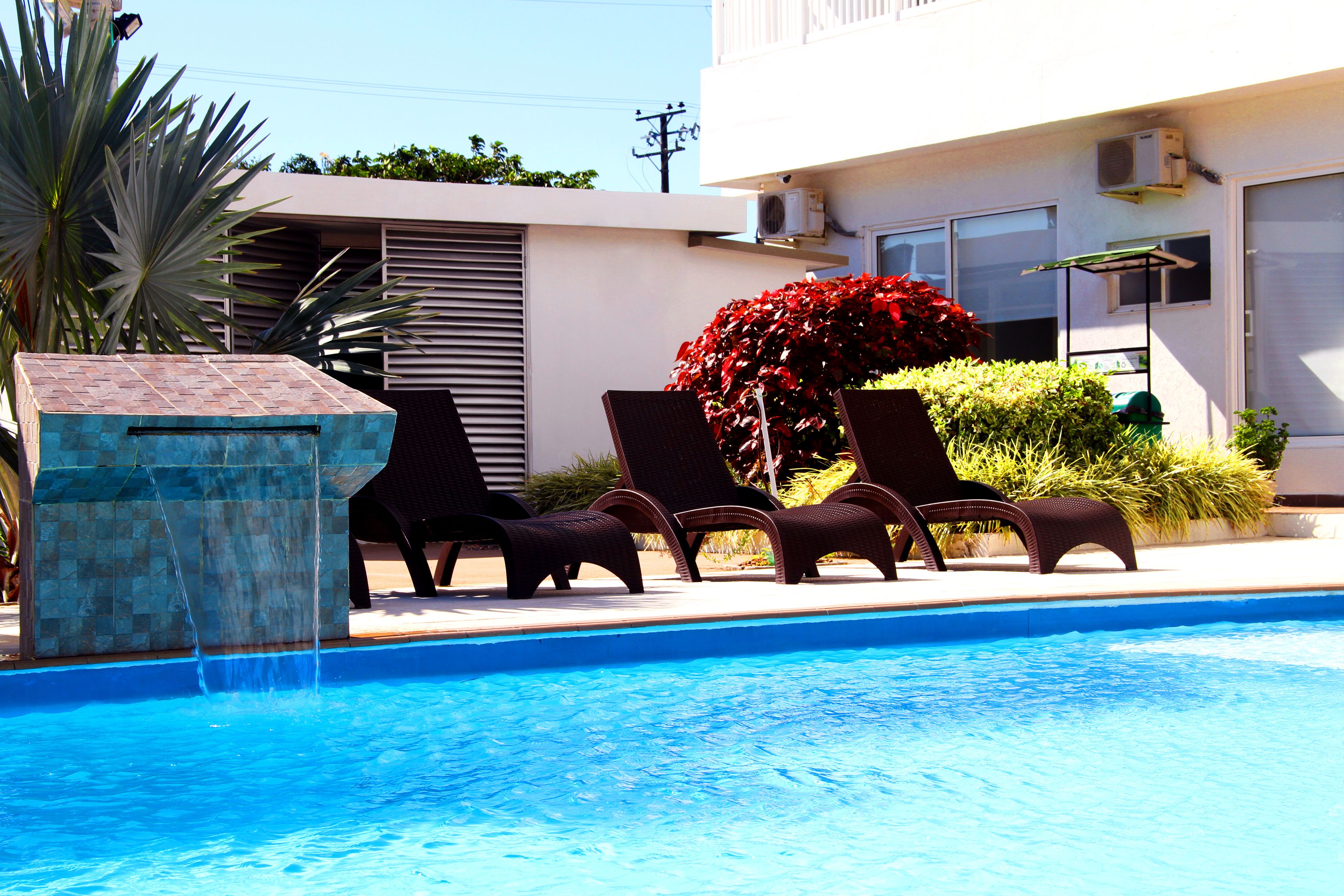 A swimming pool with lounge chairs and a water feature.