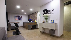 A hotel reception area with a modern design, including a reception desk, seating area, and a television screen. - Bog Urban Hotel (Bogotá)