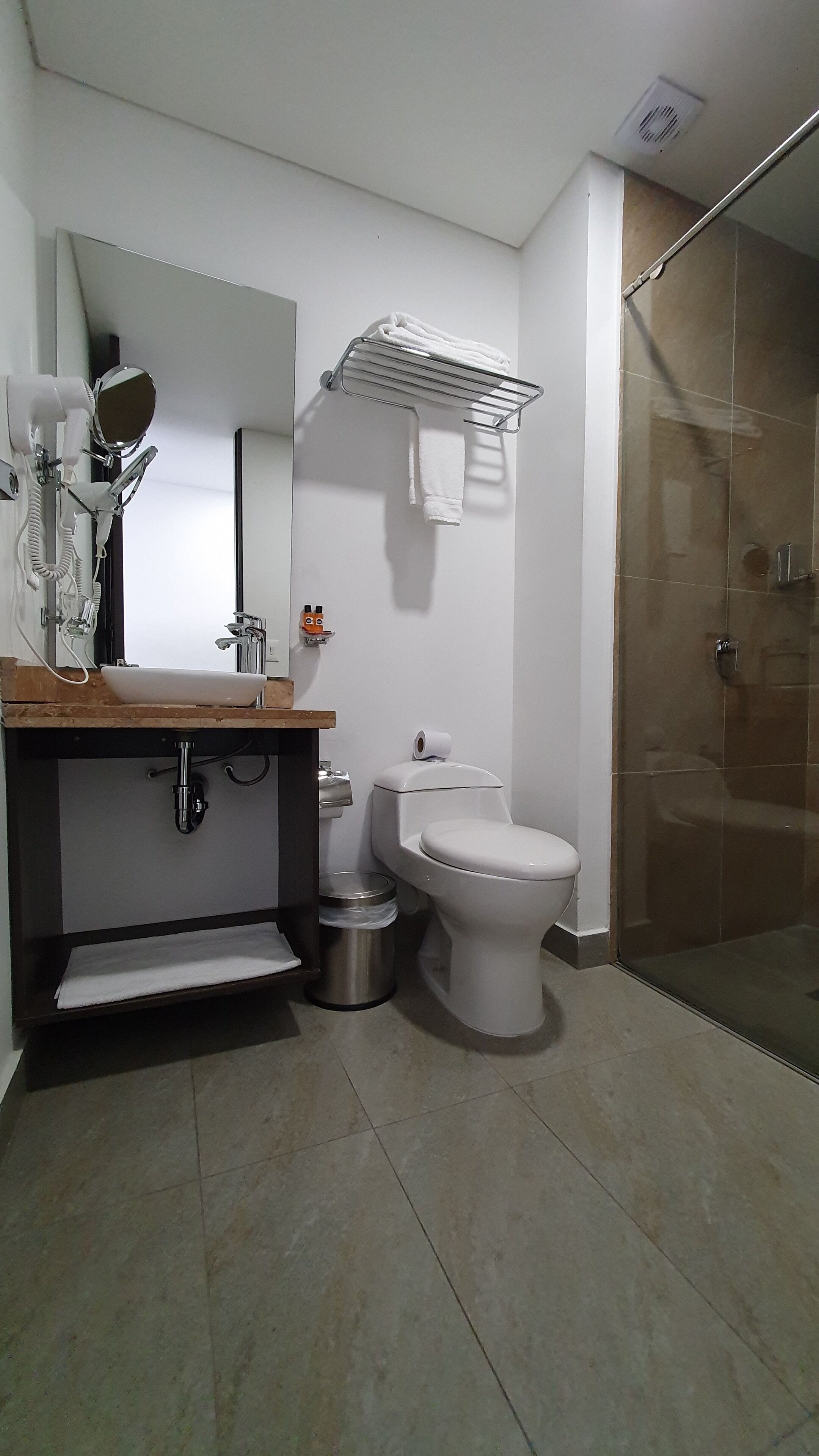 Un baño moderno con lavamanos, inodoro y ducha.