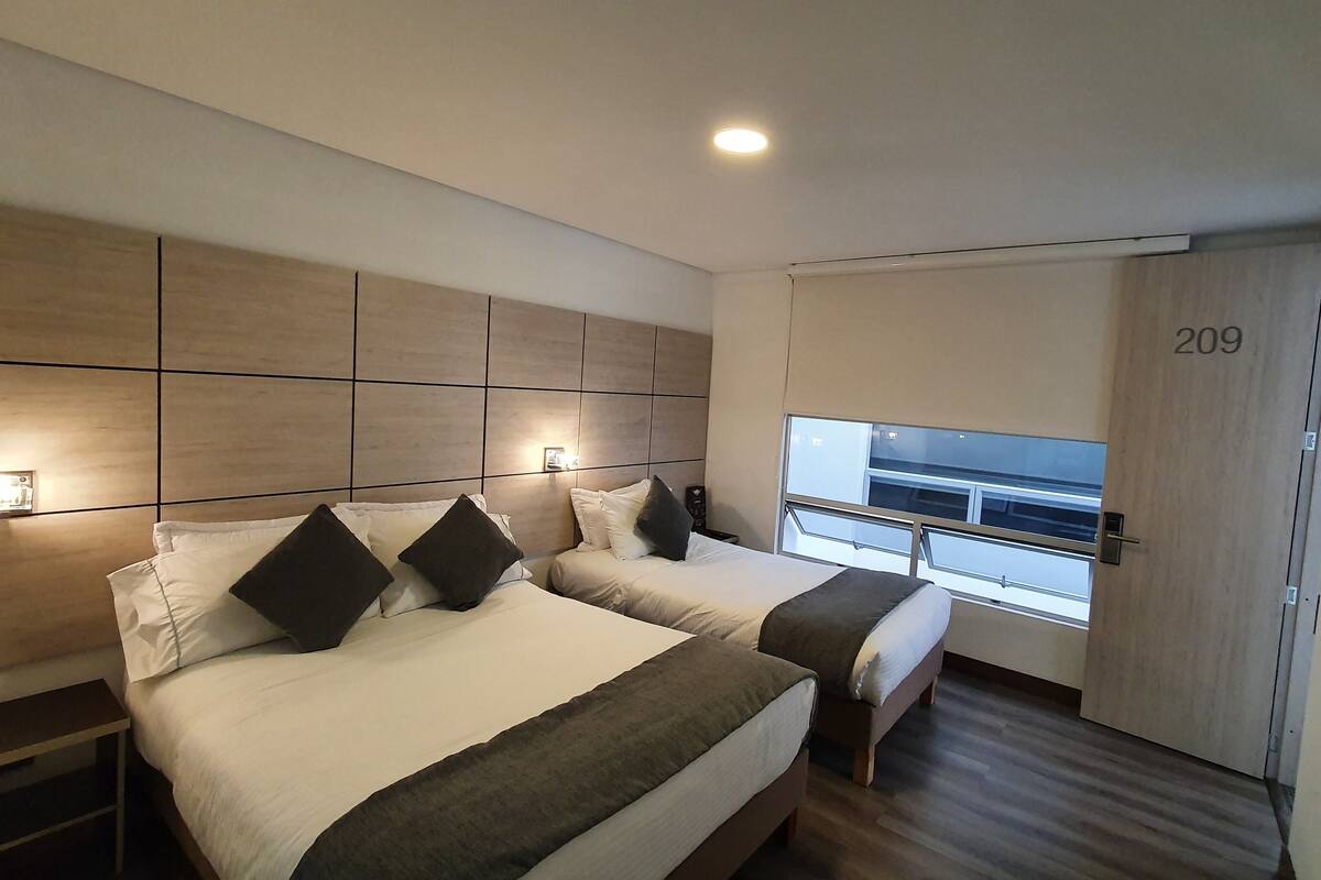 A modern hotel room with two beds, a large window, and a number 209 on the wall.