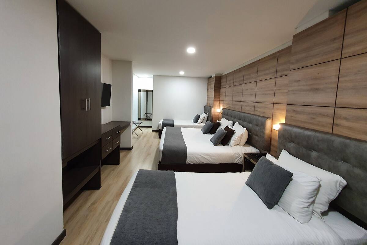 A modern hotel room with two beds, a wardrobe, a desk, and a mirror.