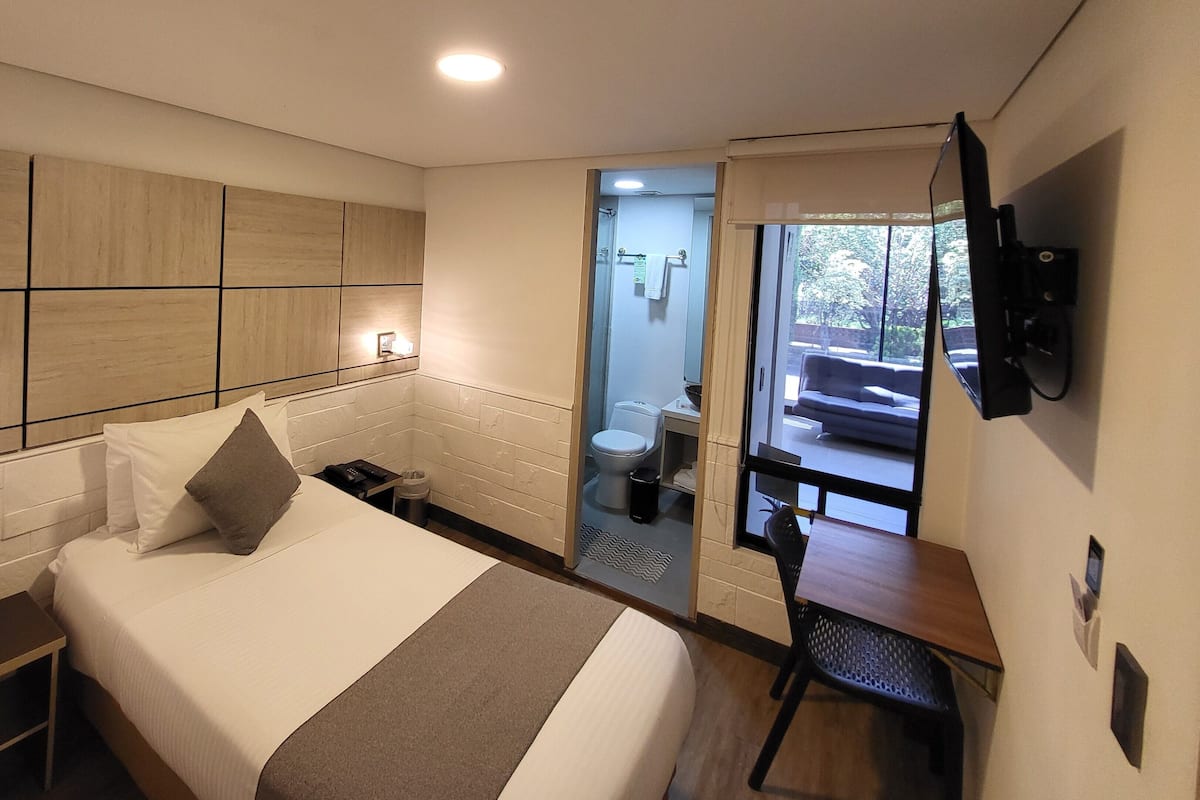 A modern hotel room with a large bed, a desk, and a TV.
