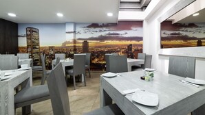 A restaurant with a cityscape mural on the wall, modern furniture, and a skylight. - Bog Urban Hotel (Bogotá)