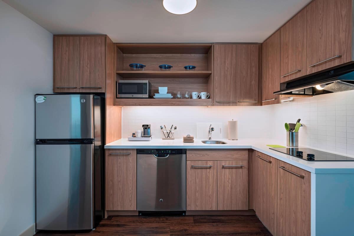 Una cocina moderna con armarios de madera, electrodomésticos de acero inoxidable y encimera blanca.