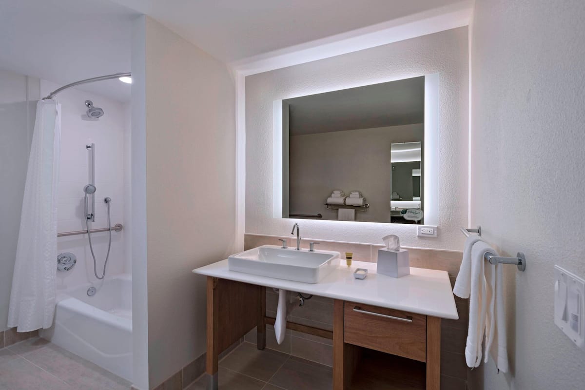 Un baño moderno con ducha, lavamanos y espejo.