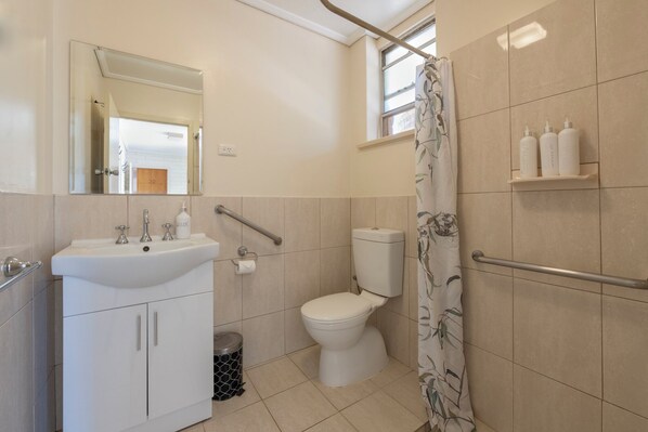 Een badkamer met een wastafel, toilet en douchegordijn.