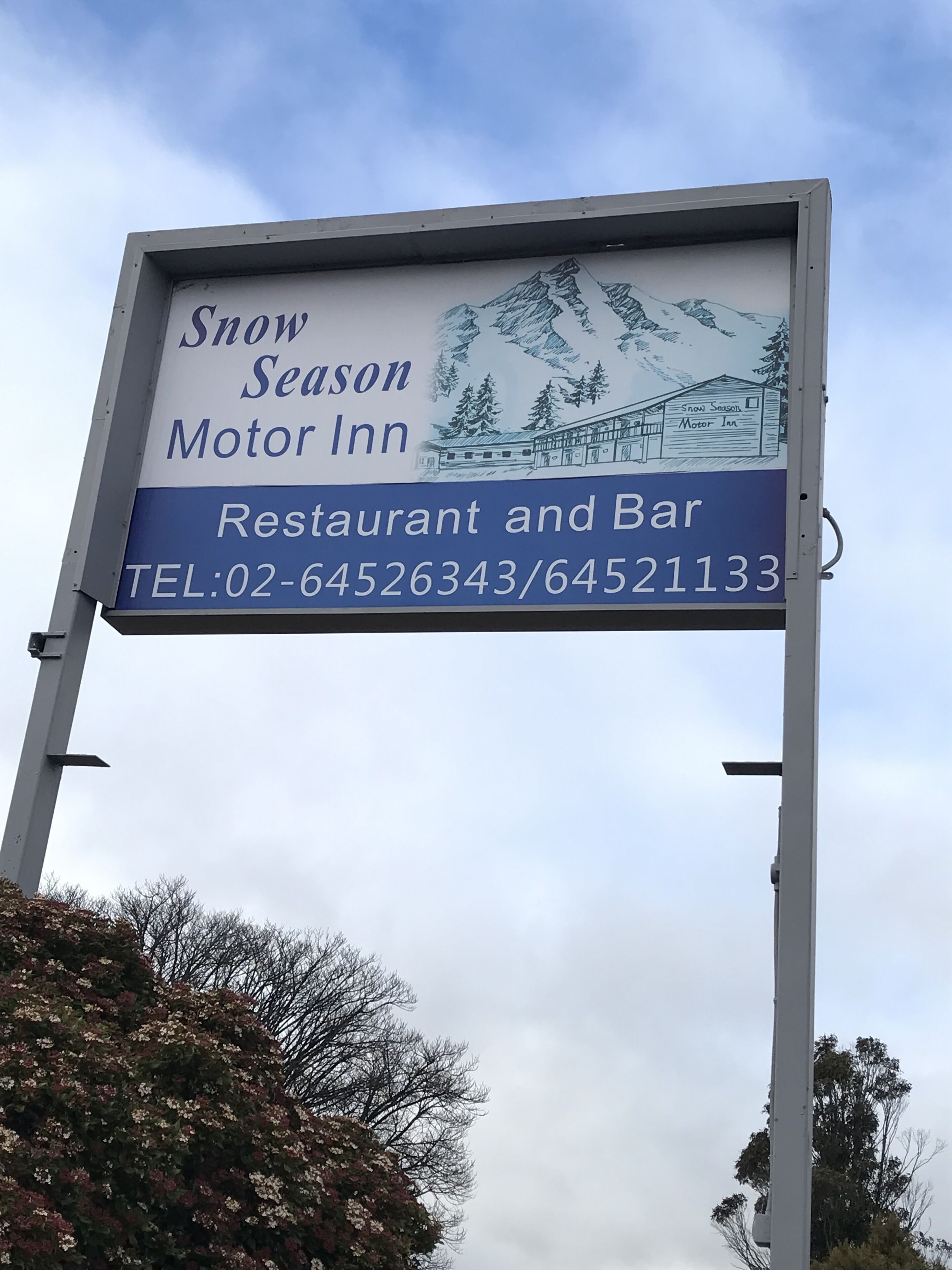 Une enseigne pour le Snow Season Motor Inn, un restaurant et un bar, avec les numéros de téléphone à contacter.