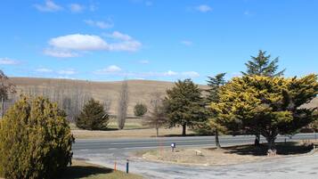 A parking lot with a road, trees, and a clear sky.