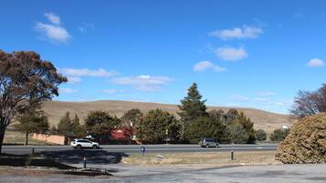 A parking lot with a red building in the background, surrounded by trees and hills.