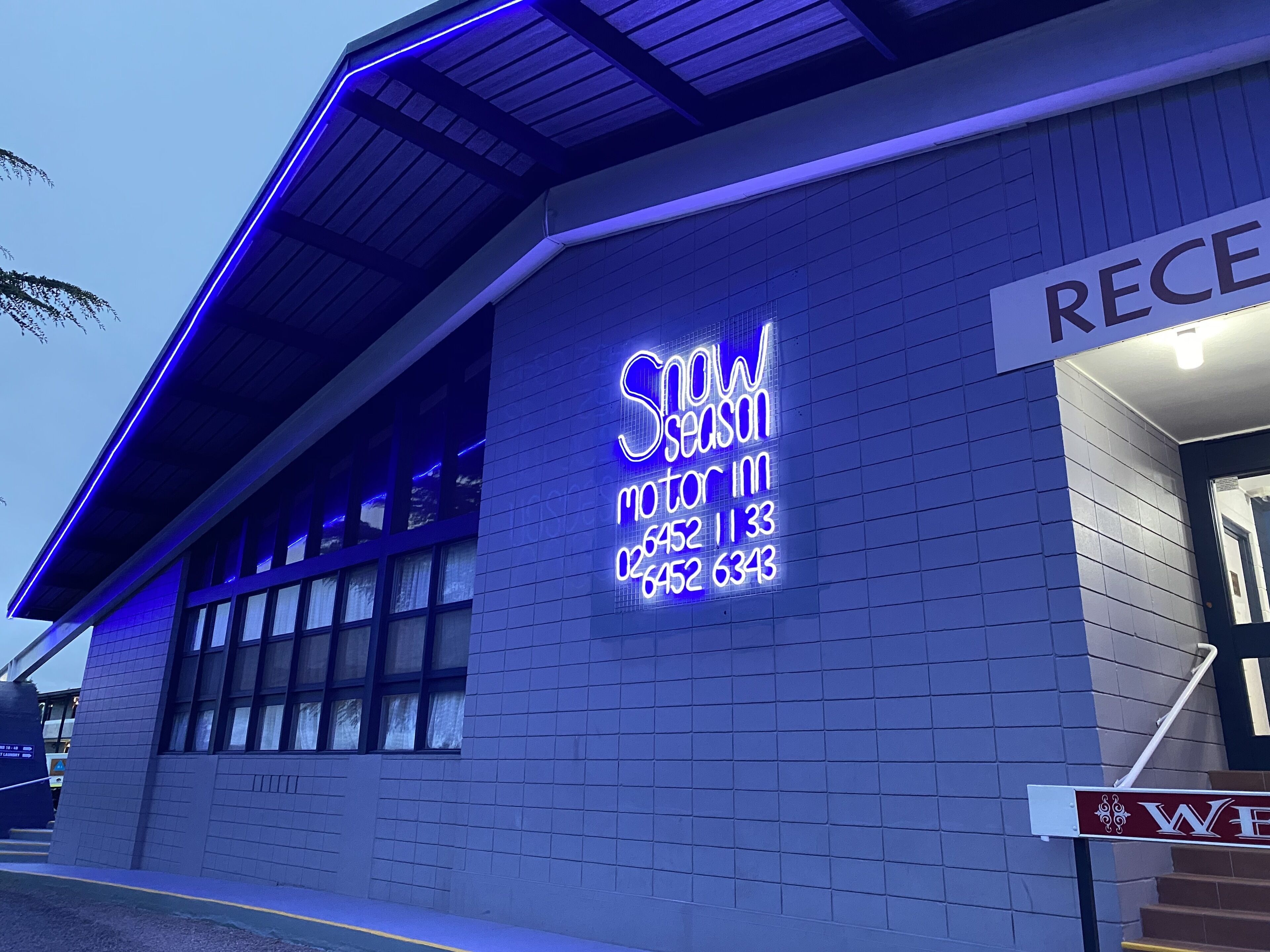 A building with a neon sign reading "Snow Season" and a reception sign.