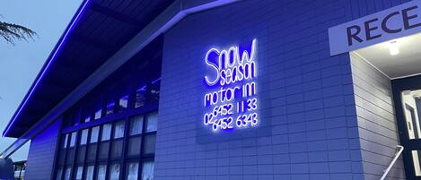 A building with a neon sign reading "Snow Season" and a reception sign.