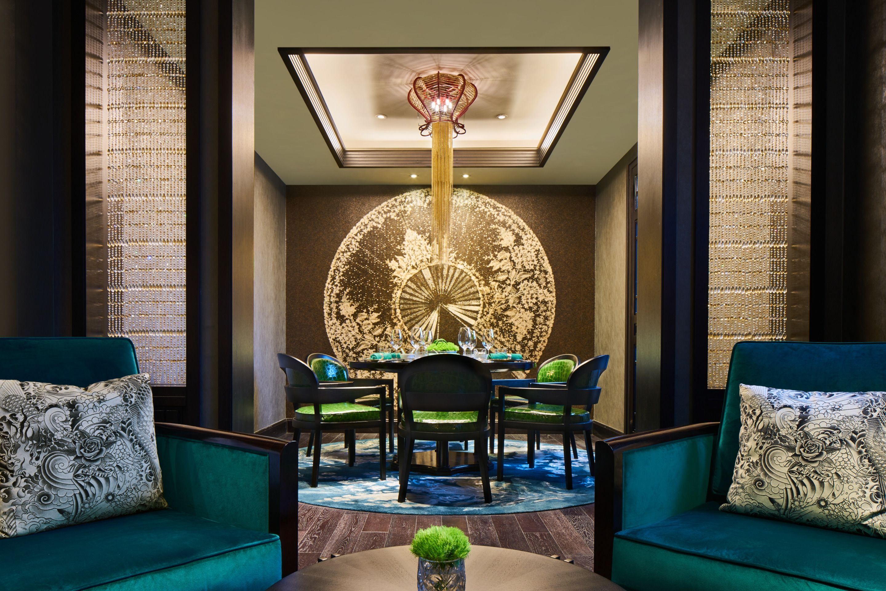 A dining area with a round table, chairs, and a chandelier.