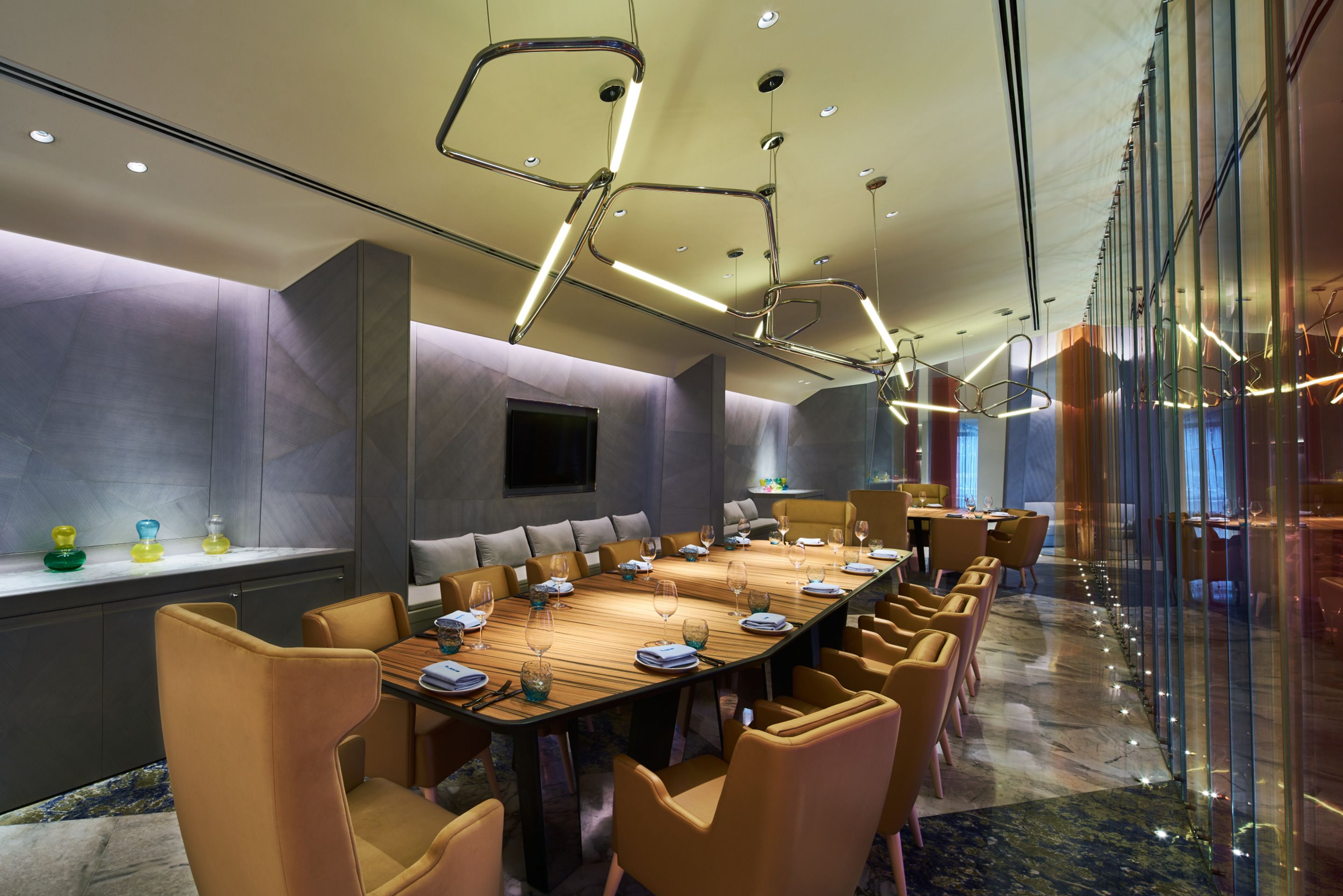 A conference room with a long table, comfortable chairs, and a modern ceiling design.