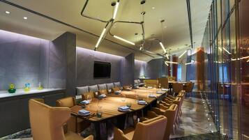 A conference room with a long table, comfortable chairs, and a modern ceiling design.