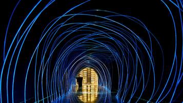 A tunnel-like structure with light trails leading to a central illuminated area.