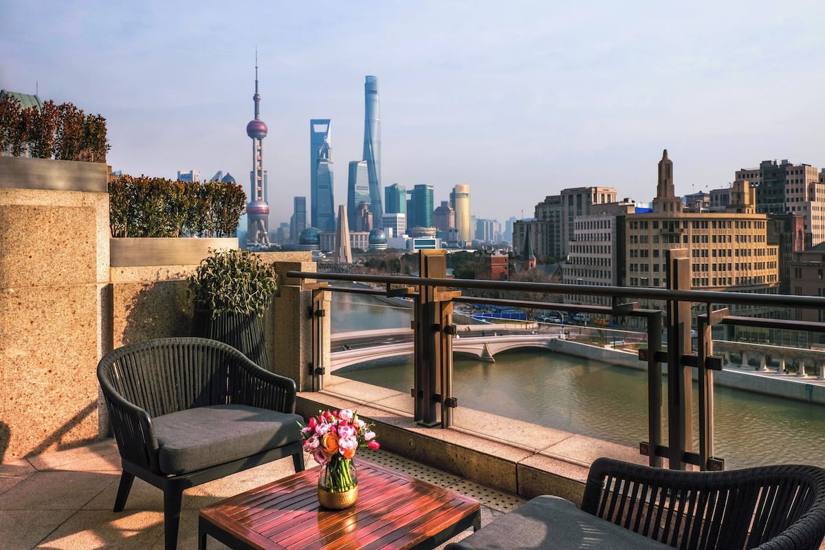 A terrace with outdoor seating, a view of a city skyline, and a river.