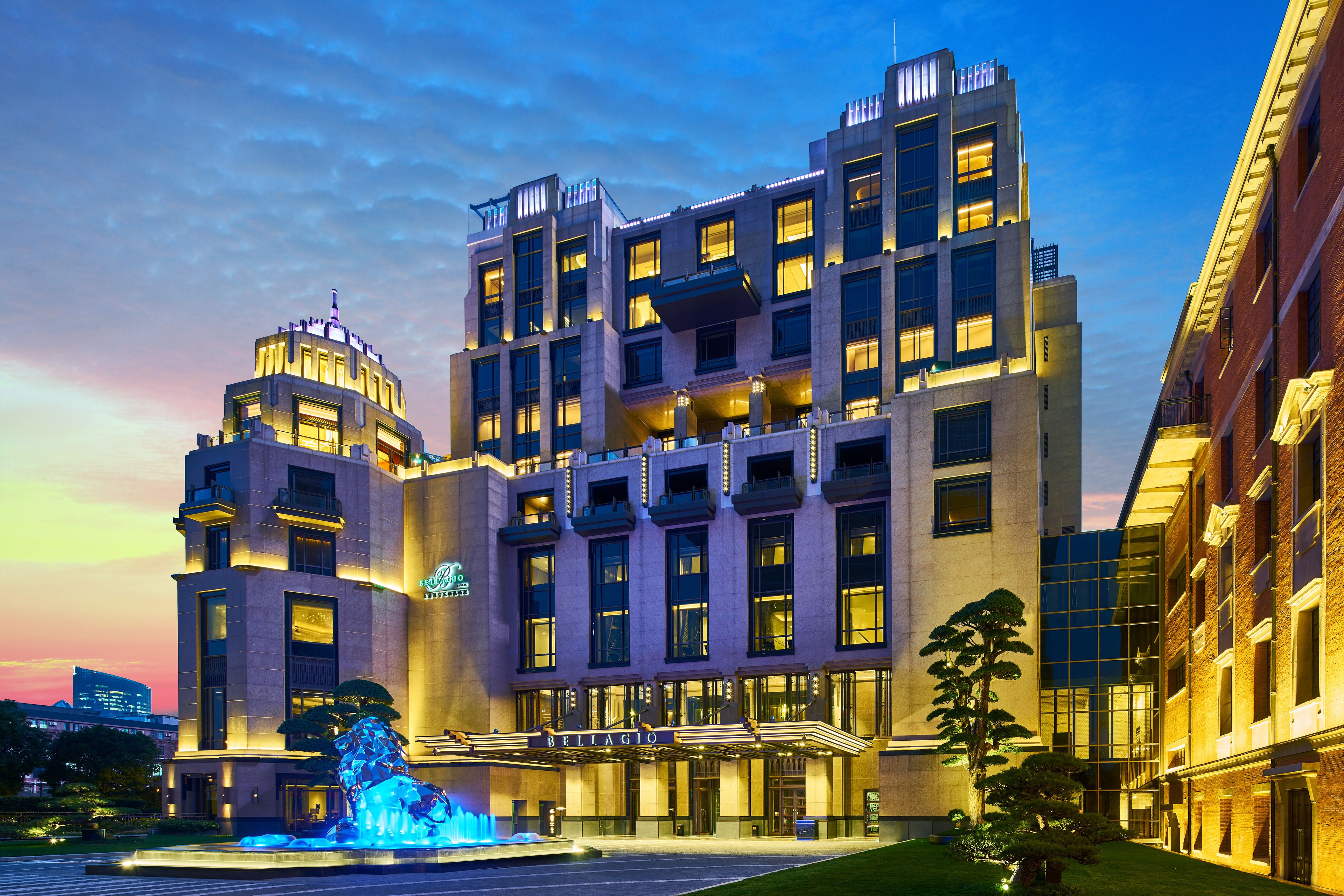 Een hotel met meerdere verdiepingen, een opvallende ingang, een fontein en een goed verlichte gevel.