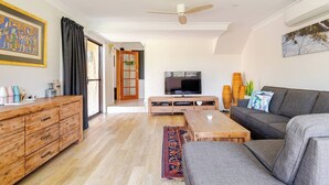 A modern living room with a sofa, TV, wooden coffee table, and a large window. - Kookaburra Retreat (Berowra Heights)
