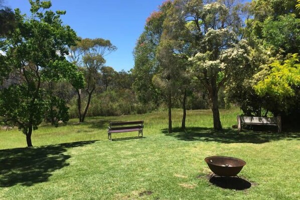 A grassy park area with a bench and a fire pit. - Kookaburra Retreat (Berowra Heights)