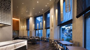 Ein geräumiges Restaurant mit hohen Decken, großen Fenstern und modernem Interieur.