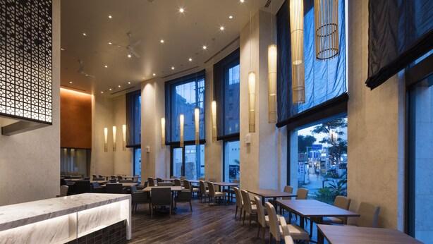 Un restaurant spacieux avec de hauts plafonds, de grandes fenêtres et un décor intérieur moderne.