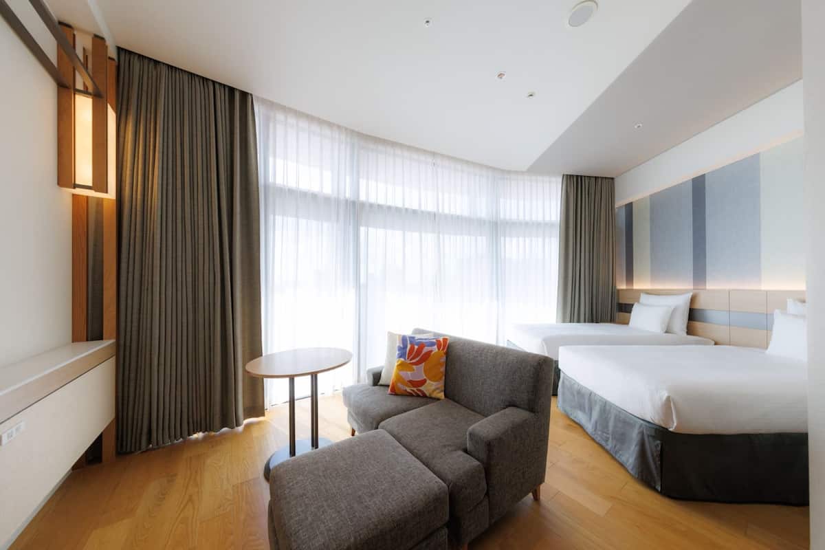 Una habitación de hotel con un sofá, una mesita y una cama.
