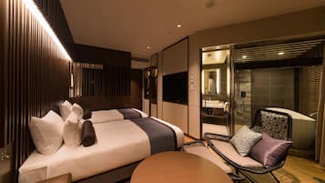 A modern hotel room with two beds, a sitting area, and a bathroom with a bathtub.