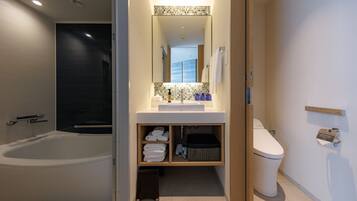 A modern bathroom with a bathtub, a toilet, and a vanity with a mirror.