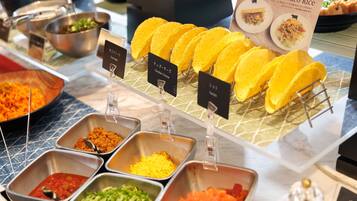 A buffet with various food options including tacos, cheese, and salsa.