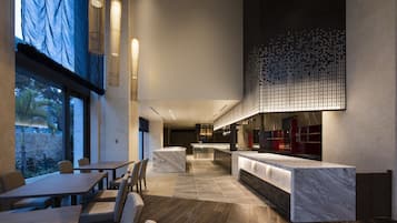 A modern interior with a long dining table, a kitchen area, and a seating area with chairs.