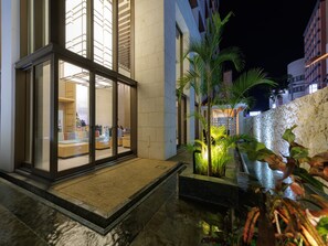 A modern hotel with a glass entrance, outdoor seating area, and a stone wall. - JR KYUSHU HOTEL Blossom Naha (Naha)
