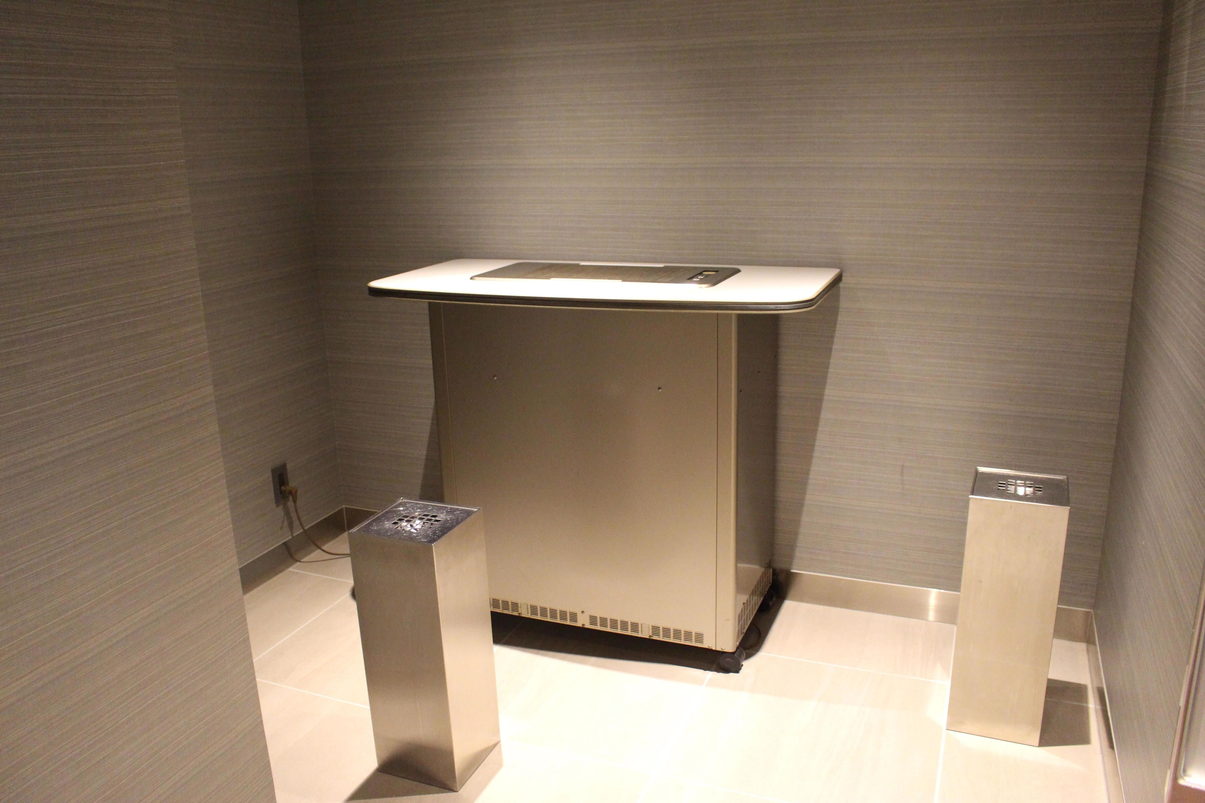 A modern, minimalist bathroom with a large sink, a mirror, and a small trash bin.