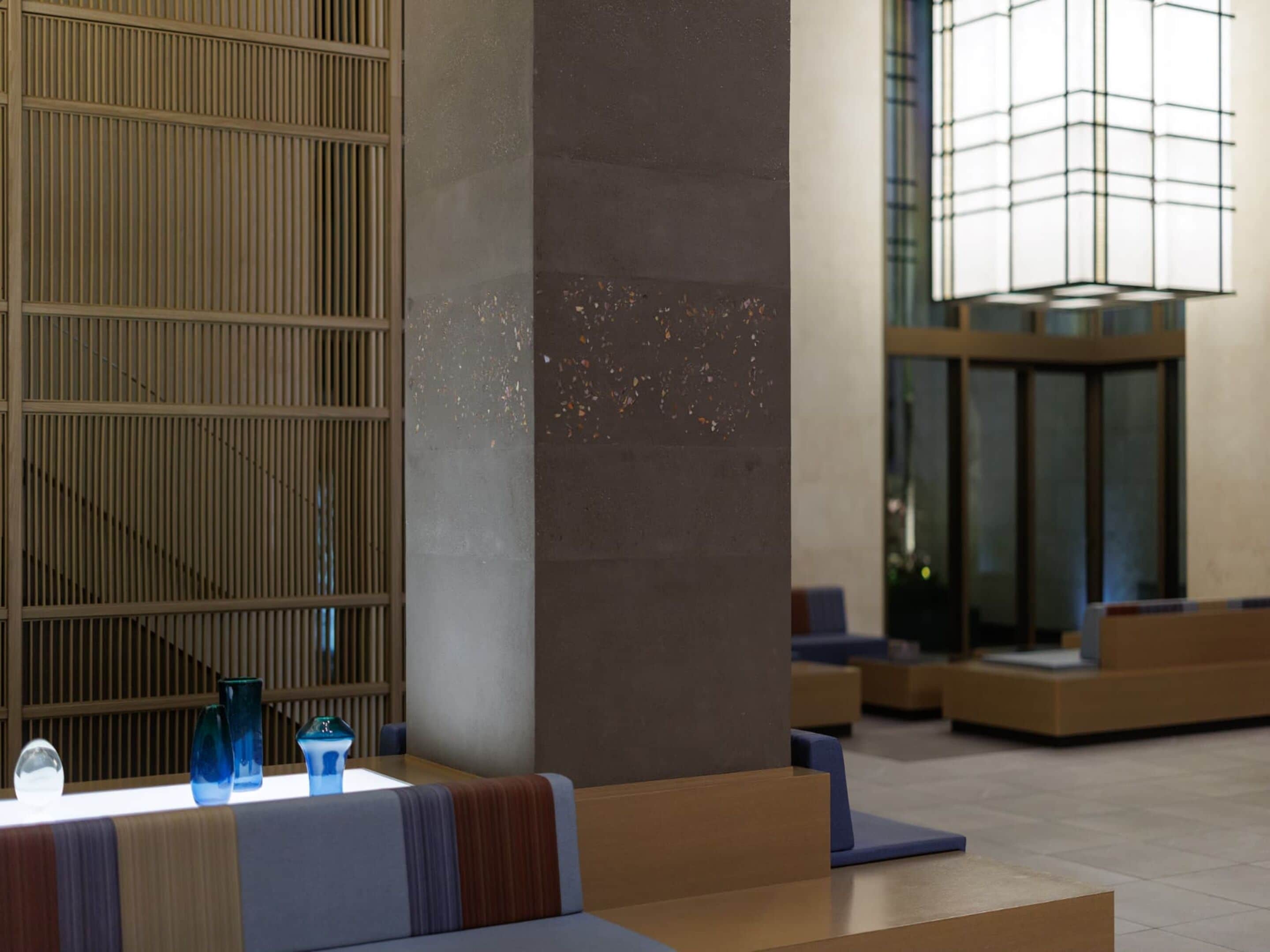A modern lobby with a seating area, a decorative column, and a large window with a view.