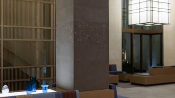 A modern lobby with a seating area, a decorative column, and a large window with a view.