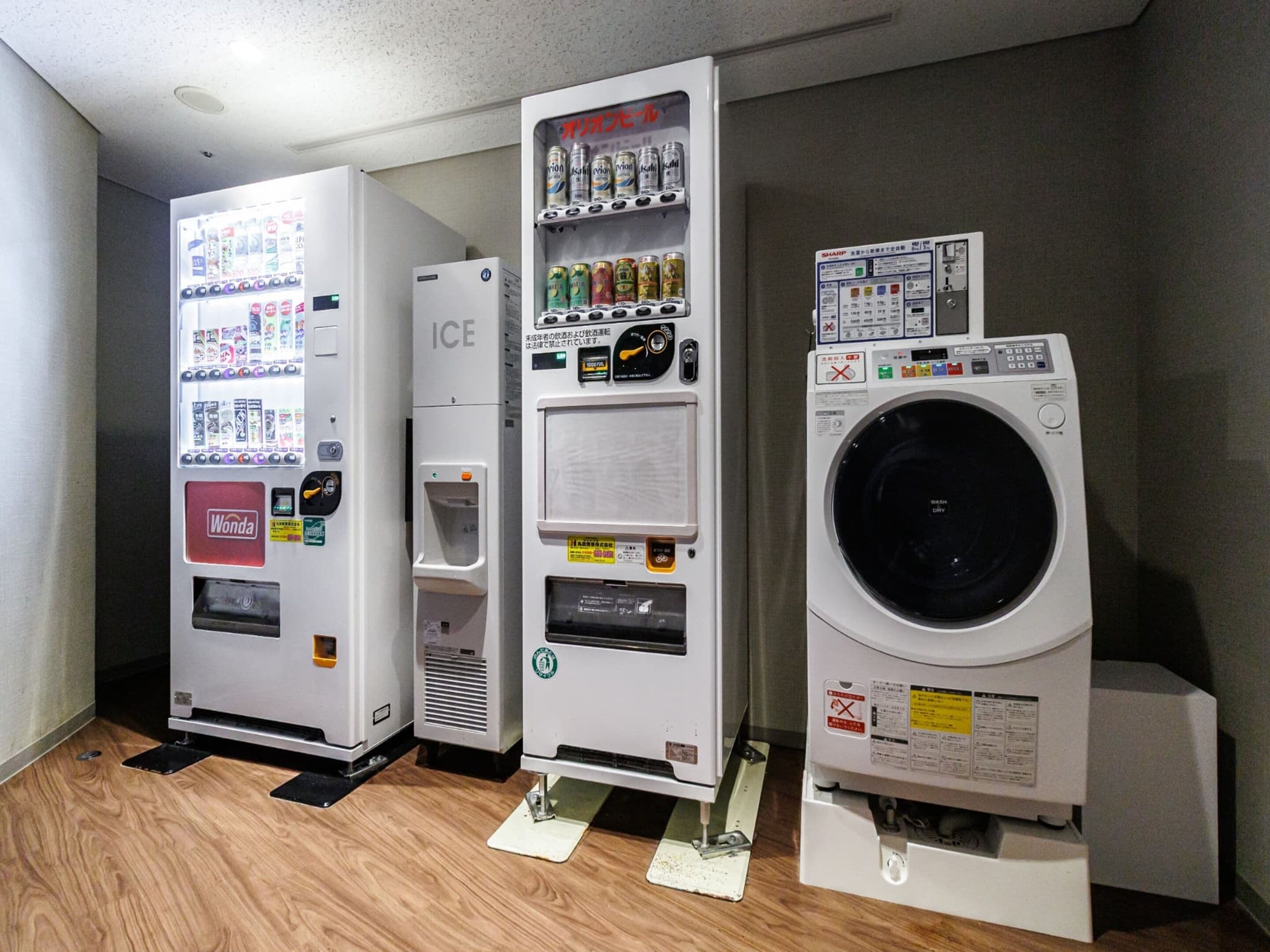 Máquina de vendas automática, dispensador de gelo e máquina de lavar num quarto.