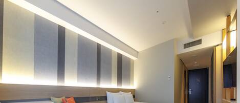 Una habitación de hotel moderna con una cama grande, un área de descanso con una mesa y una pared grande con rayas verticales.